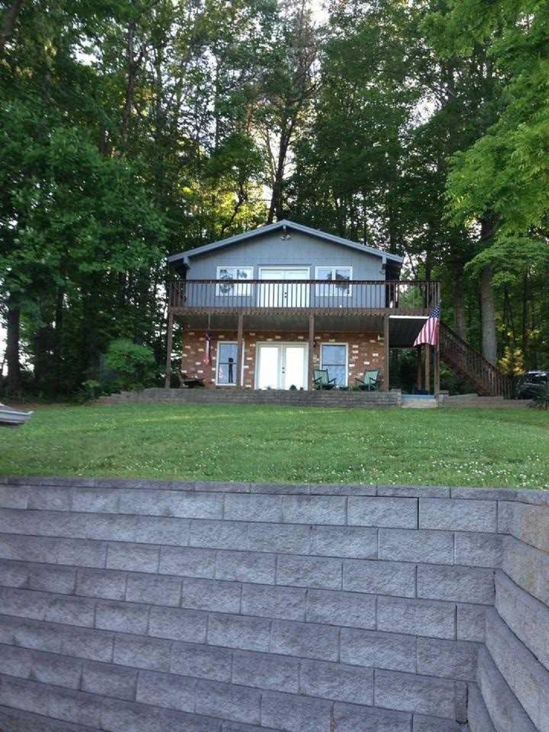 a view of a house with a yard and large trees