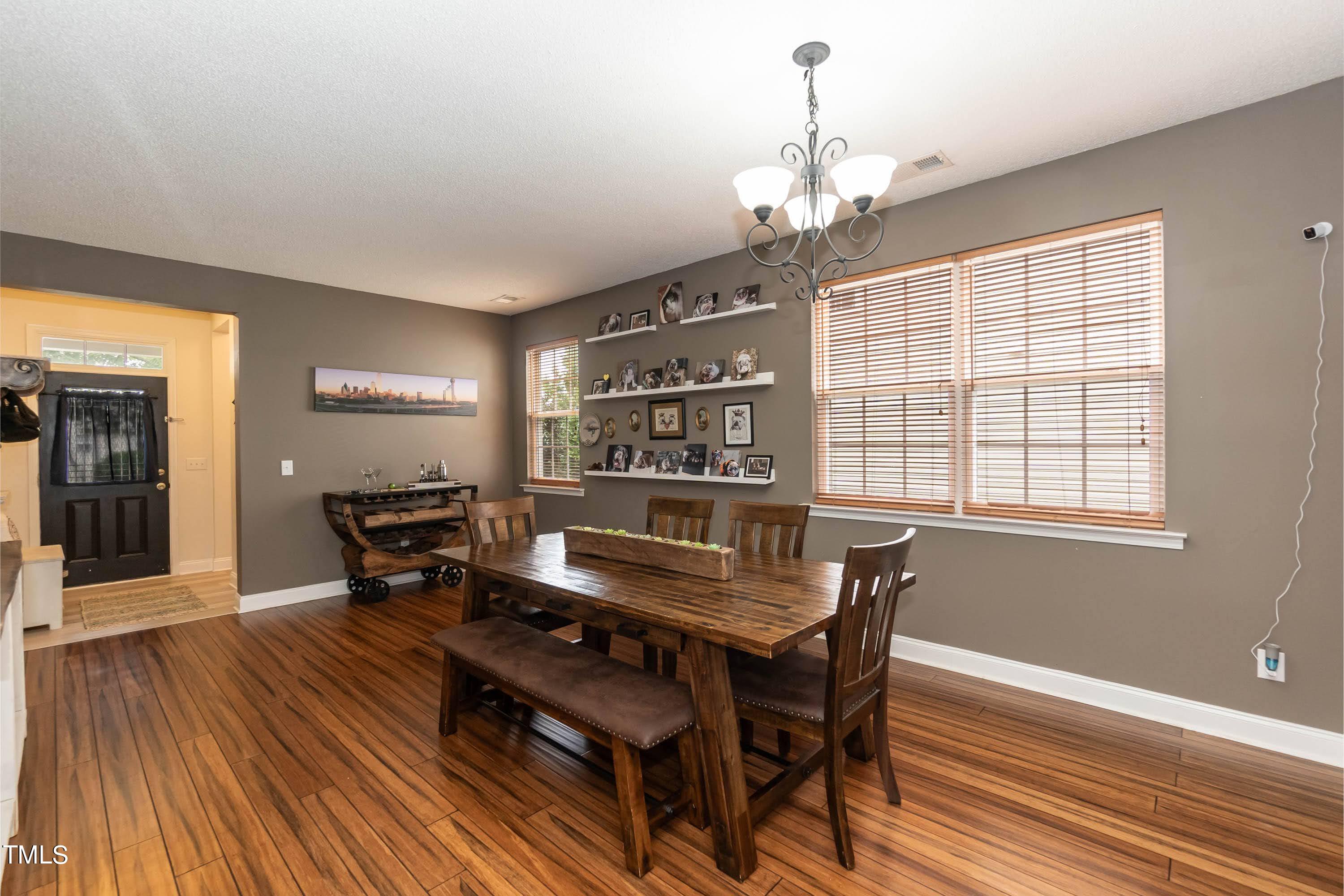 108 Solheim Lane Raleigh, NC 27603 - Photo 12 of 49 a dining room with wooden floor a chandelier a wooden table and chairs