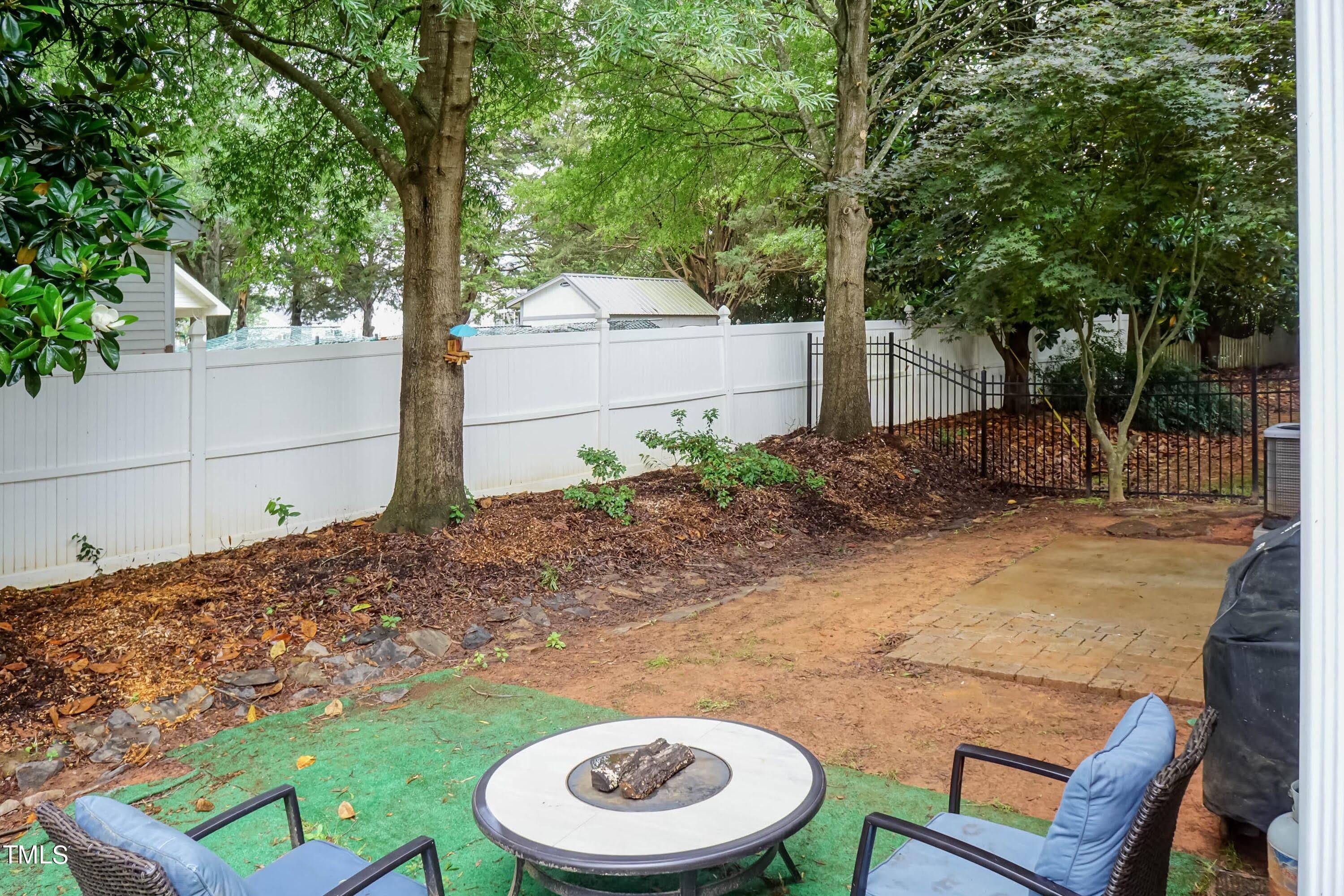 108 Solheim Lane Raleigh, NC 27603 - Photo 36 of 49 a backyard of a house with table and chairs a barbeque and a large tree