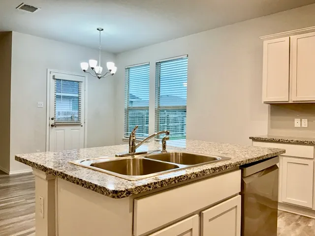 a kitchen with granite countertop a sink and white cabinets