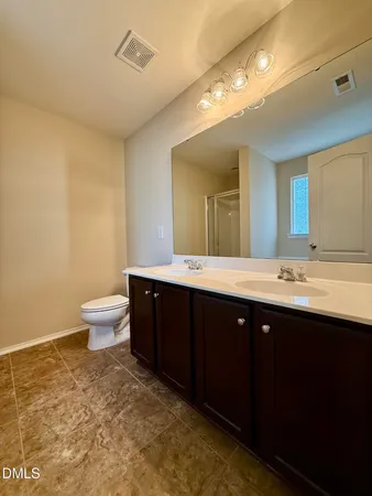 a spacious bathroom with a double vanity sink toilet and a mirror