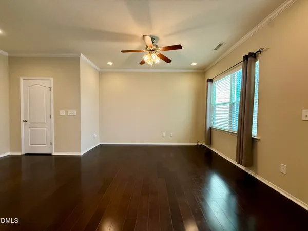 an empty room with wooden floor fan and windows