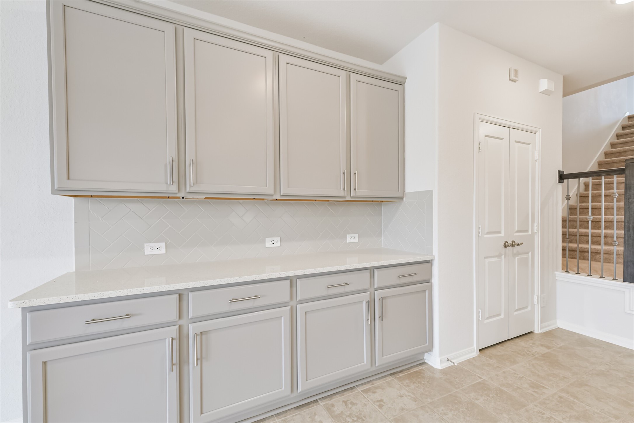 2129 Solstice Boulevard Spring, TX 77386 - Photo 14 of 49 Extended kitchen cabinetry offers excellent storage and counter space, complete with sleek hardware, a herringbone backsplash, and neutral-tone finishes. Perfect for a coffee bar, serving area, or extra pantry space.