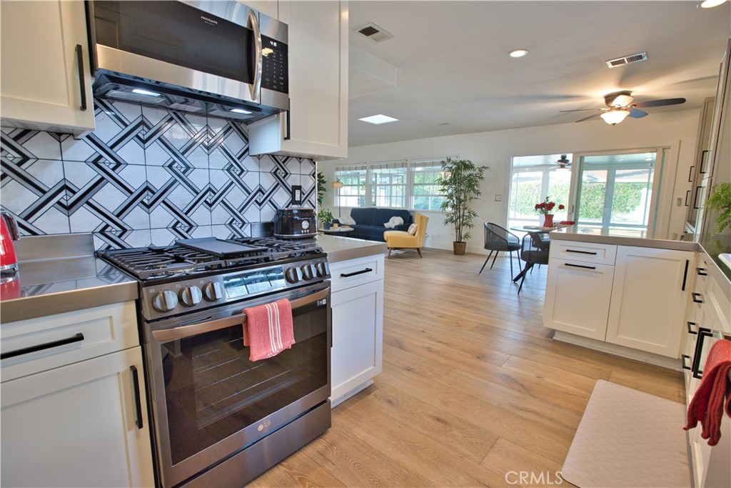 6091 Dundee Drive Huntington Beach, CA 92647 - Photo 13 of 55 a kitchen with stainless steel appliances granite countertop a stove and a wooden floors