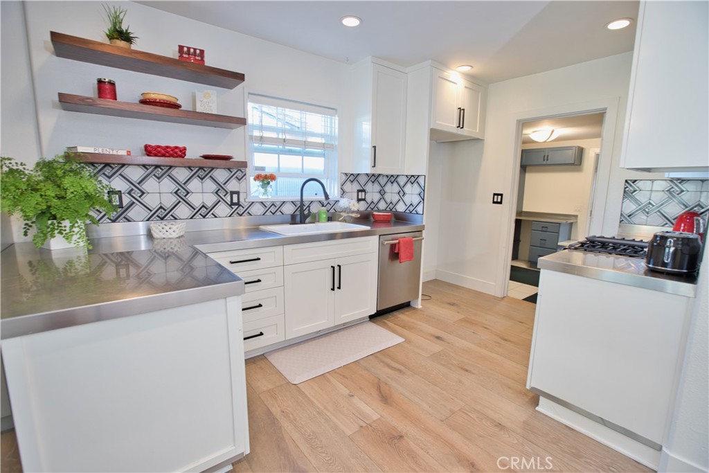 6091 Dundee Drive Huntington Beach, CA 92647 - Photo 30 of 55 a kitchen with cabinets a sink and a stove with wooden floor