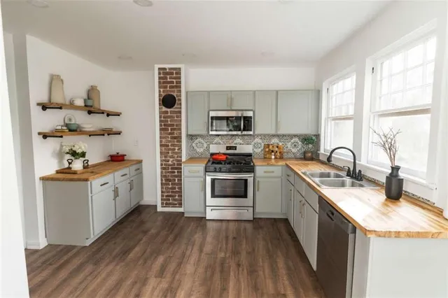 a kitchen with stainless steel appliances granite countertop a stove a sink dishwasher and a refrigerator with wooden floor