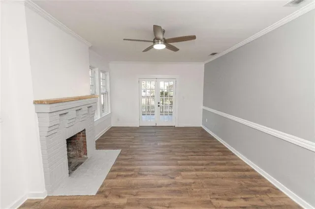 a view of an empty room with wooden floor fireplace and a window