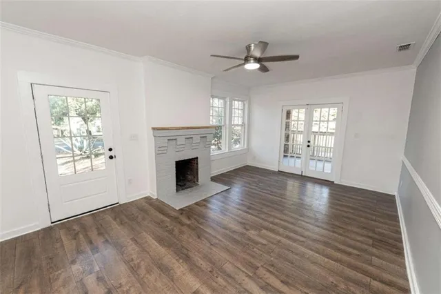 an empty room with windows fireplace and wooden floor