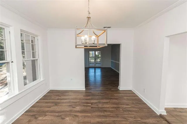 a view of a hallway with wooden floor and chandelier
