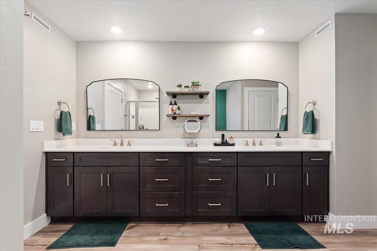 815 Knowledge Street Middleton, ID 83644 - Photo 27 of 49 Dual vanities featuring dark wood cabinetry, white countertops, and undermount sinks