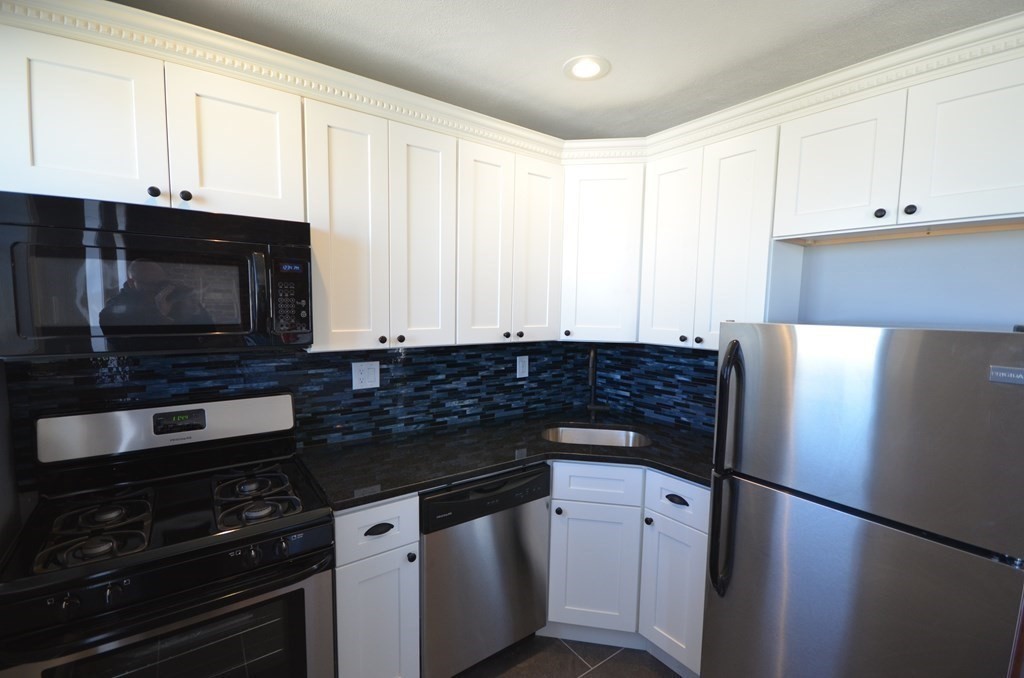 a kitchen with granite countertop white cabinets and black appliances