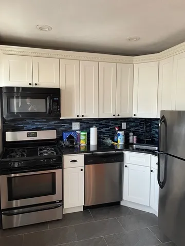 a kitchen with stainless steel appliances a stove a microwave and white cabinets