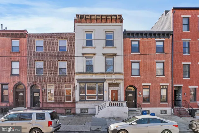 a front view of a building with lot of cars and trees