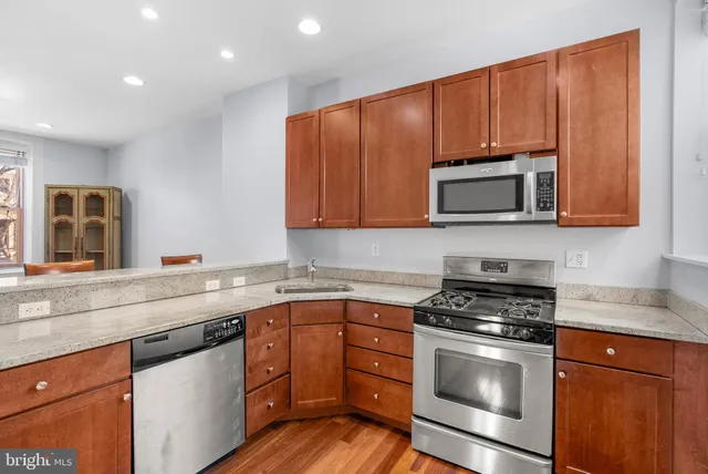 a kitchen with granite countertop wooden cabinets stainless steel appliances and a window