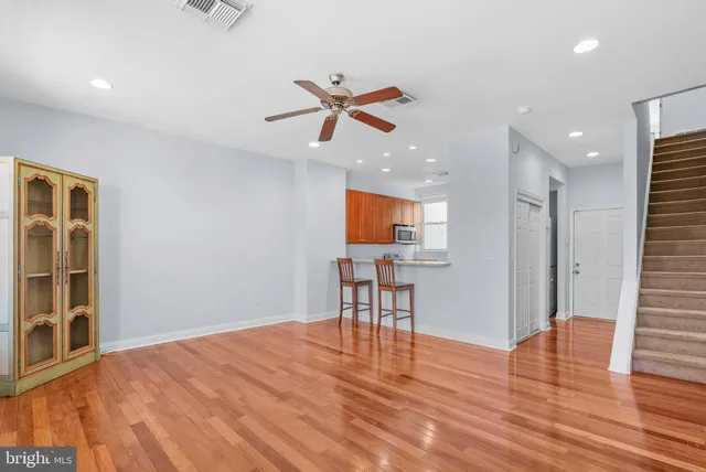 a view of a room with wooden floor and a ceiling fan
