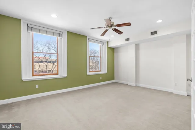 a view of an empty room with window and ceiling fan