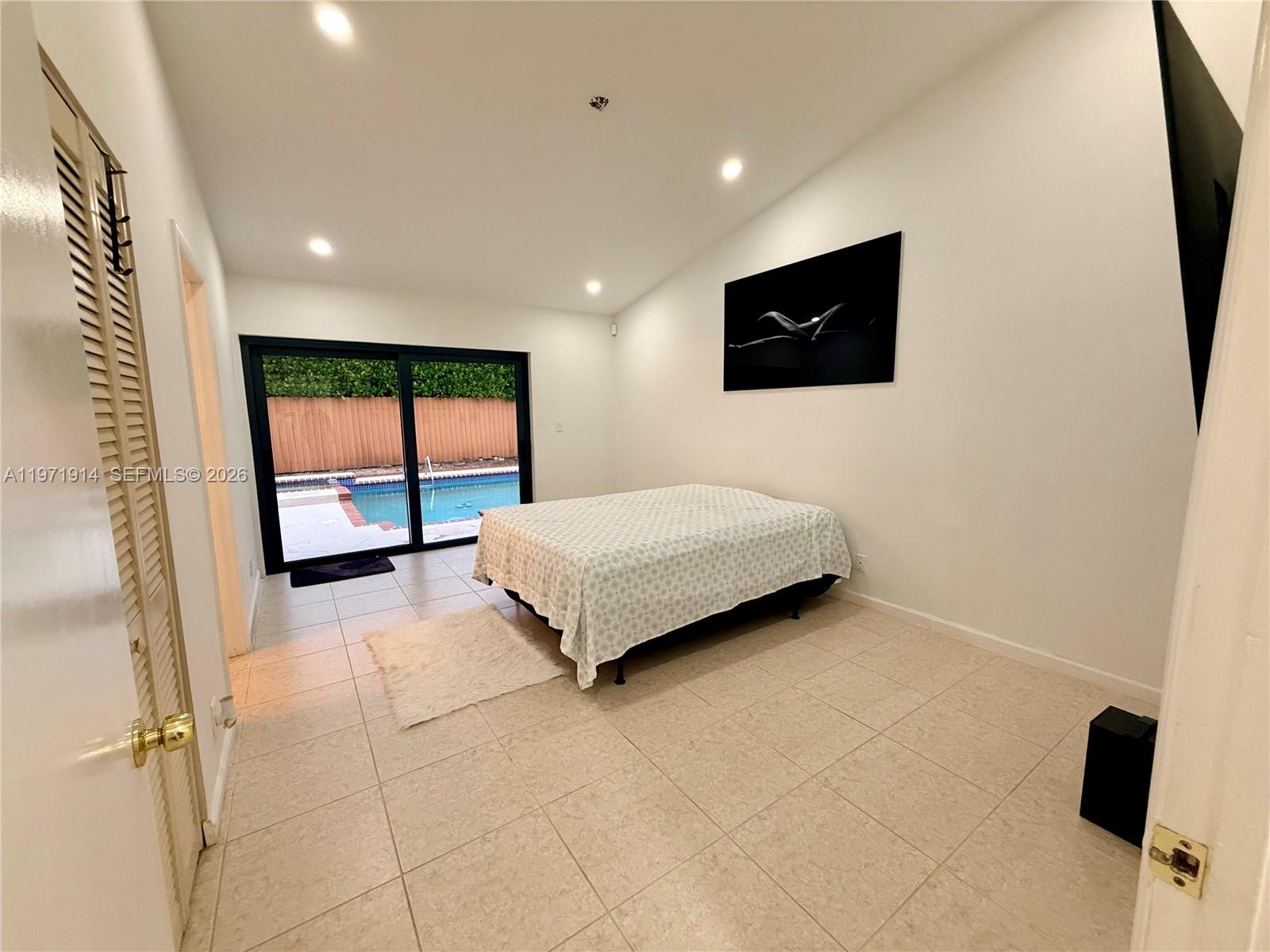 13253 Southwest 96th Terrace Miami, FL 33186 - Photo 13 of 18 a bedroom with a bed a tv on wall and a window