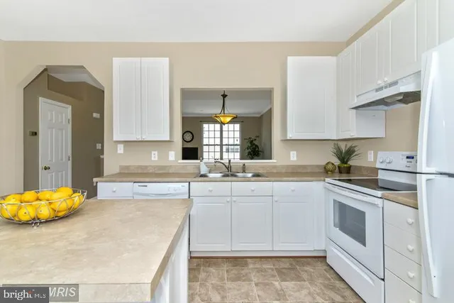 a kitchen with a sink a stove a refrigerator and white cabinets with wooden floor