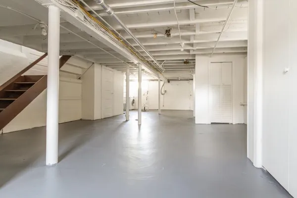 a view of an empty room with wooden floor and staircase