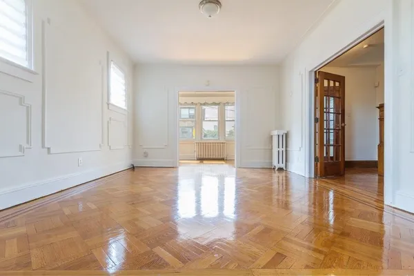 a view of an empty room with window and wooden floor