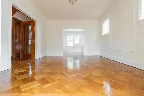 a view of empty room with wooden floor and fan