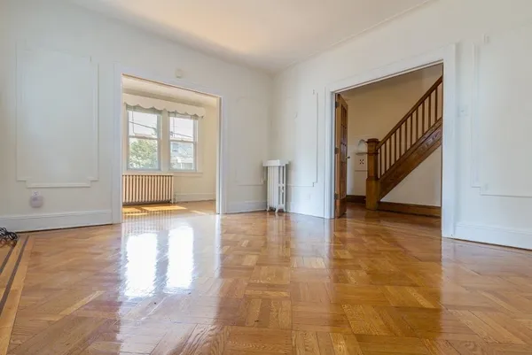 a view of an empty room with window and wooden floor