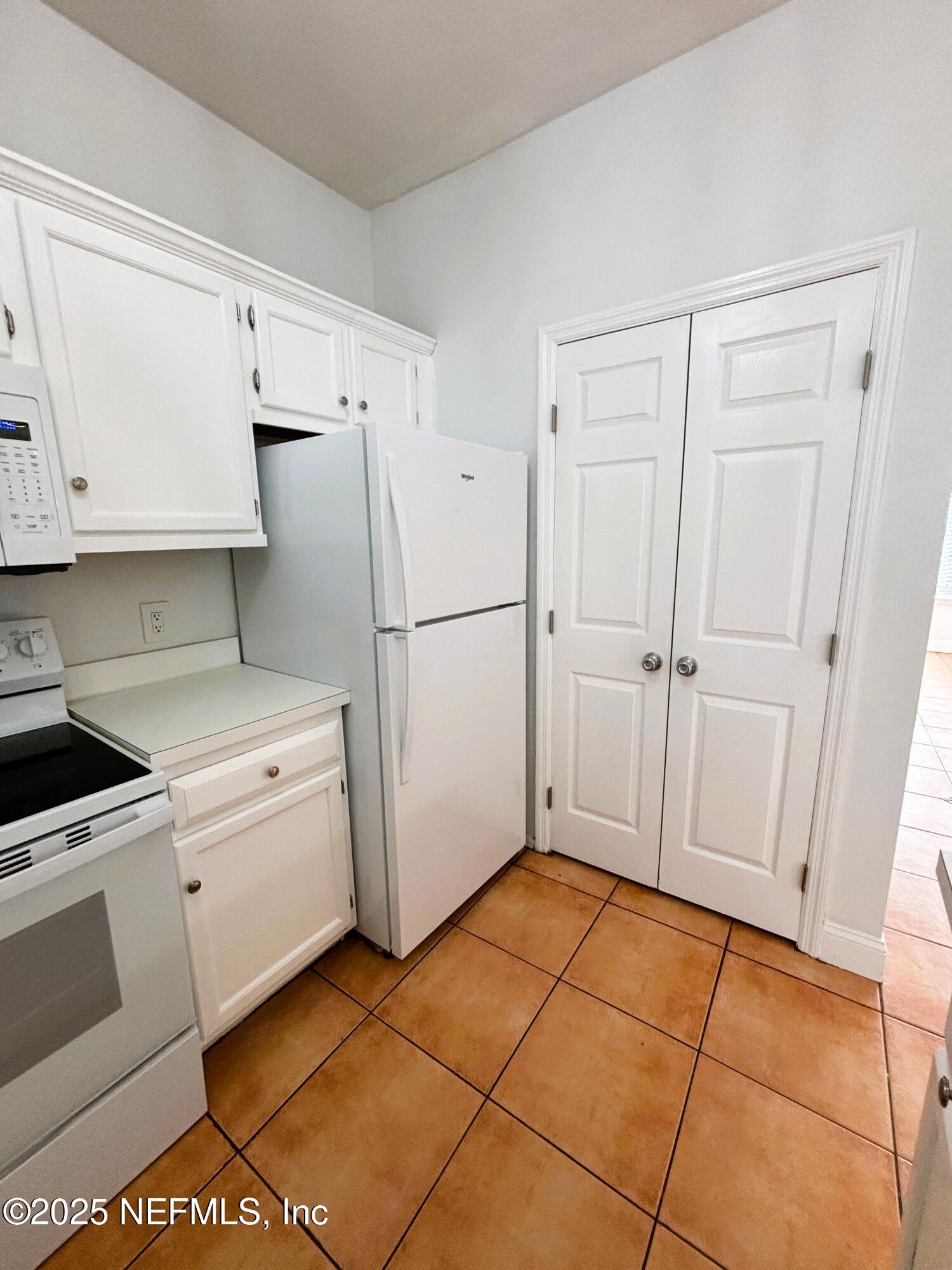 201 Colima Court, Unit 1211 Ponte Vedra Beach, FL 32082 - Photo 3 of 35 a kitchen with white cabinets and white appliances