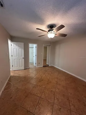 a view of an empty room with chandelier fan