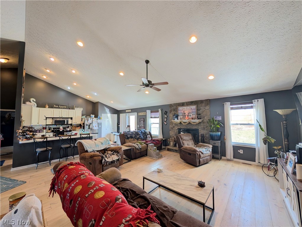 7360 Jones Road Nashport, OH 43830 - Photo 11 of 29 Living area featuring a stone fireplace, light wood-style flooring, recessed lighting, plenty of natural light, and ceiling fan