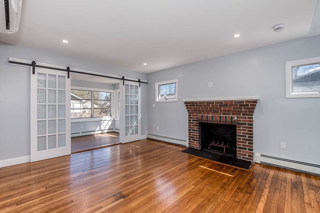 43 Shore Avenue Wareham, MA 02571 - Photo 5 of 40 an empty room with wooden floor fireplace and windows