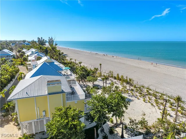an aerial view of ocean and residential houses with outdoor space