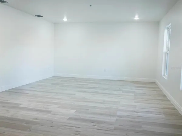 a view of an empty room with wooden floor and a window