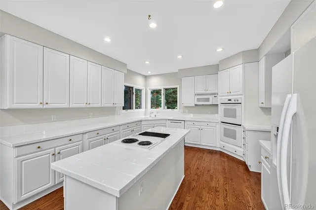a kitchen that has a lot of white cabinets and stainless steel appliances
