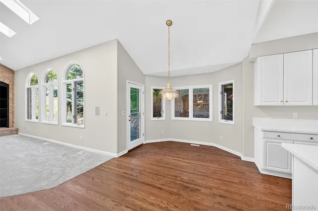 a view of an empty room with window and wooden floor