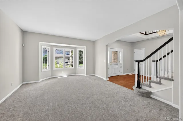 a view of an empty room with stairs and a window
