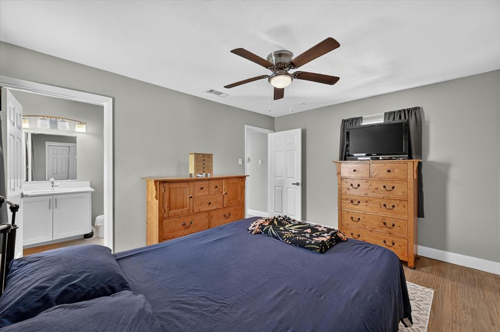 5906 Rocky Ridge Road Dallas, TX 75241 - Photo 22 of 35 Bedroom featuring wood-finish flooring, a ceiling fan with integrated lighting, and a private en-suite bathroom with a white vanity and wall-mounted light fixture