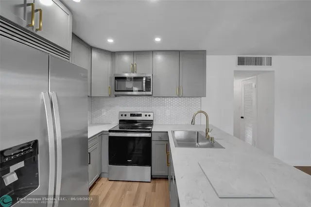a kitchen with stainless steel appliances a stove a sink a refrigerator and cabinets