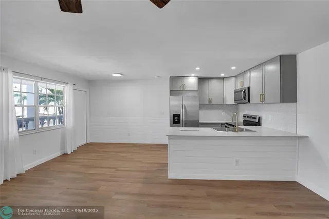 a large kitchen with stainless steel appliances granite countertop a stove a sink and white cabinets