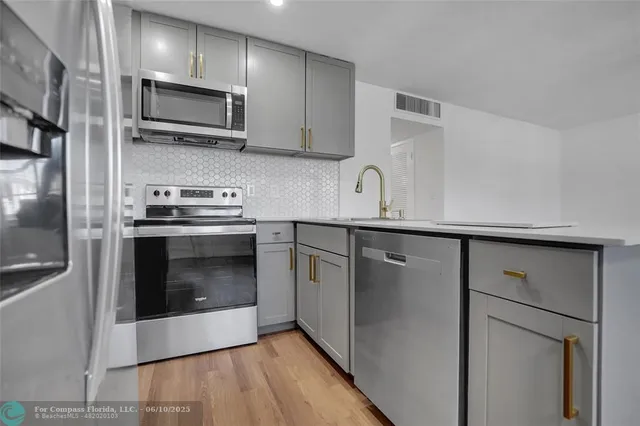 a kitchen with stainless steel appliances a stove a microwave and a hard wood floor