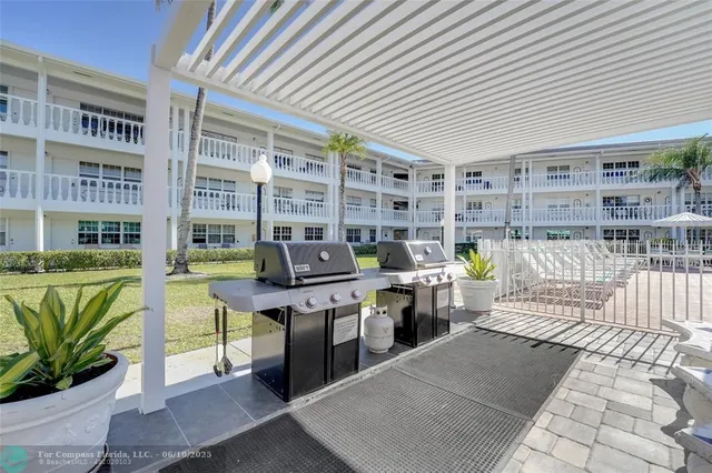 a open kitchen with stainless steel appliances granite countertop a table chairs and a barbeque grill