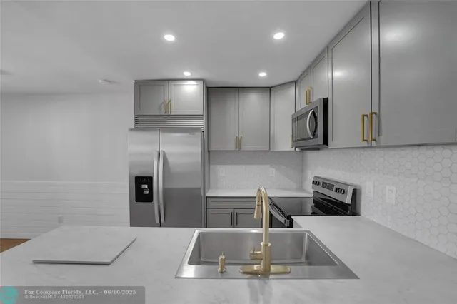 a kitchen with stainless steel appliances granite countertop a sink and a refrigerator
