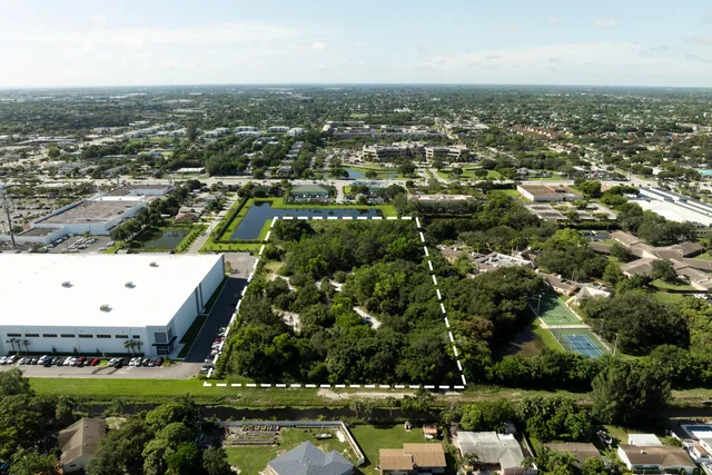 an aerial view of a residential houses with outdoor space and trees