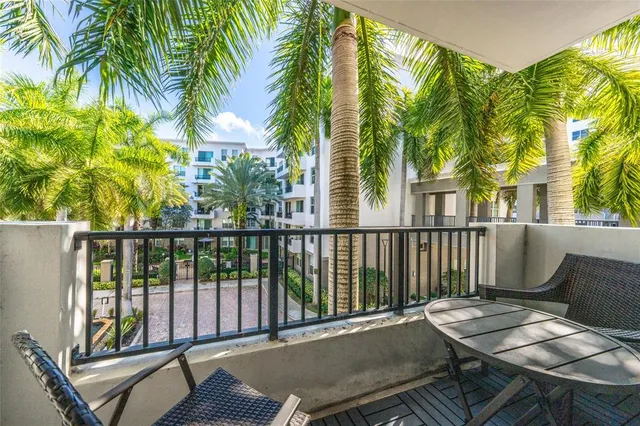 a balcony with table and chairs and potted plants
