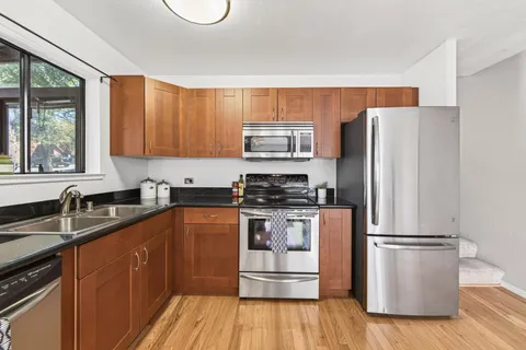 a kitchen with granite countertop a refrigerator stove top oven and sink