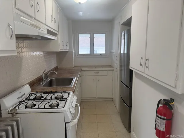 a white kitchen with stainless steel appliances granite countertop a stove and a sink