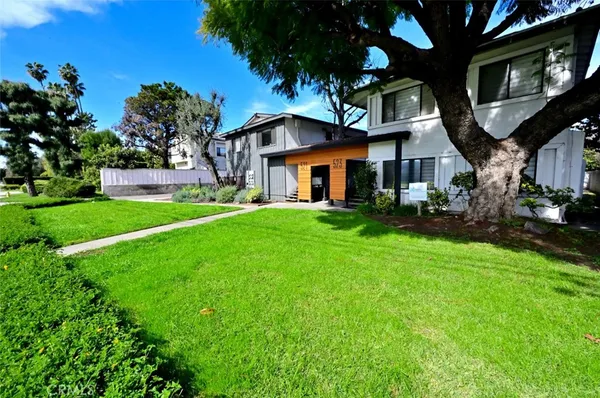 a front view of a house with a yard and palm trees
