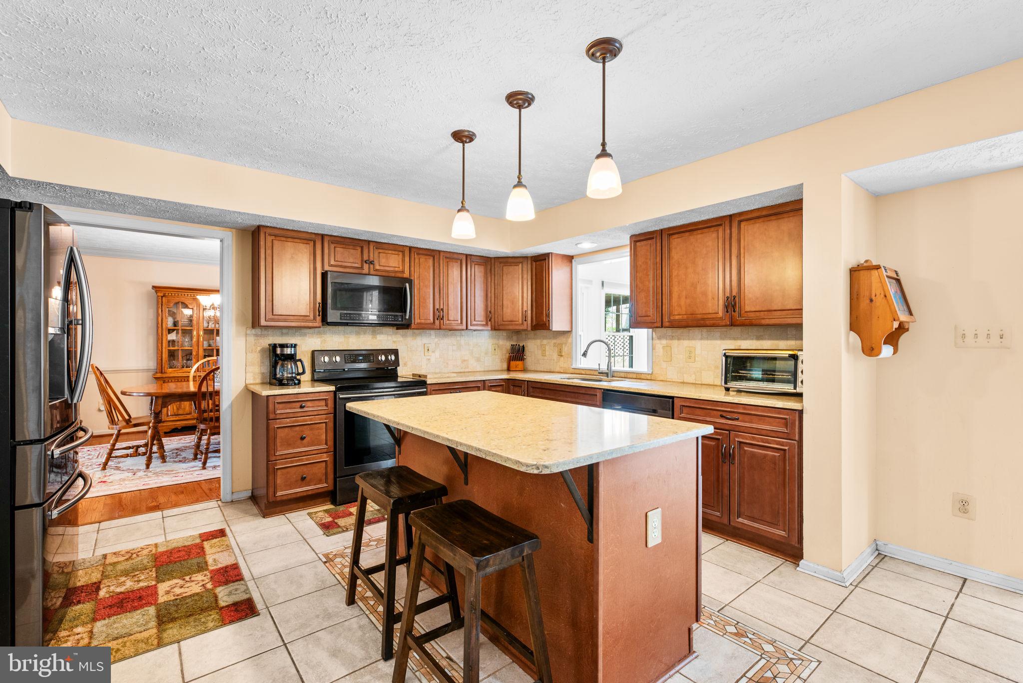 9464 Joppa Pond Road Baltimore, MD 21234 - Photo 15 of 66 a kitchen with stainless steel appliances granite countertop a stove top oven a refrigerator a sink a dining table and chairs with the cabinets