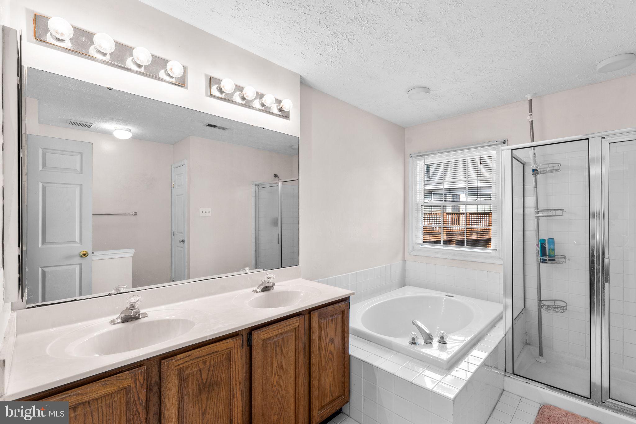 9464 Joppa Pond Road Baltimore, MD 21234 - Photo 36 of 66 a bathroom with a tub a double vanity sink and mirror