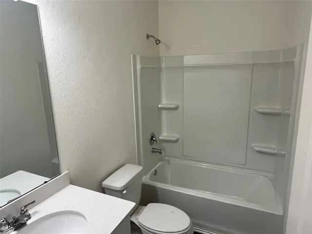 a white toilet and tub sitting next to a bathroom sink