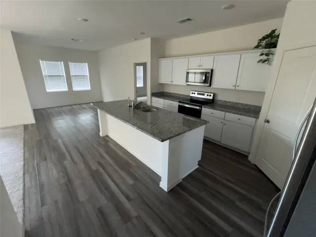 a kitchen with granite countertop a sink stove and refrigerator